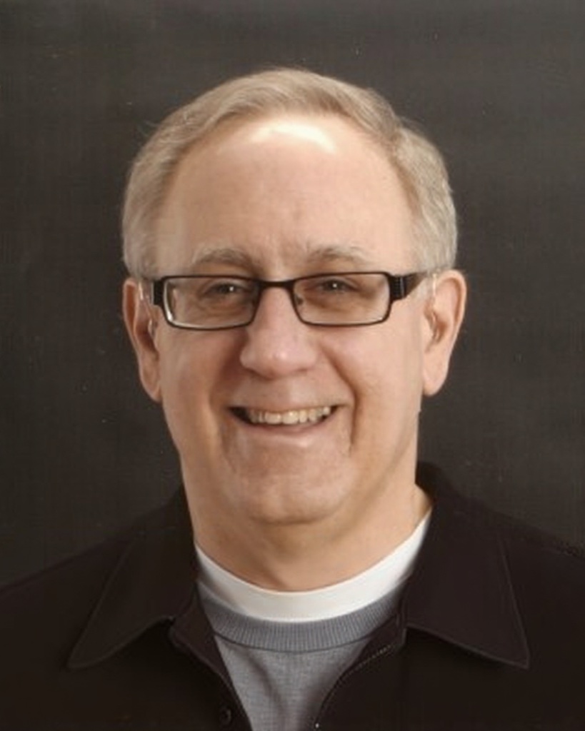 Keith Gormezano, smiling, in glasses and a dark jacket